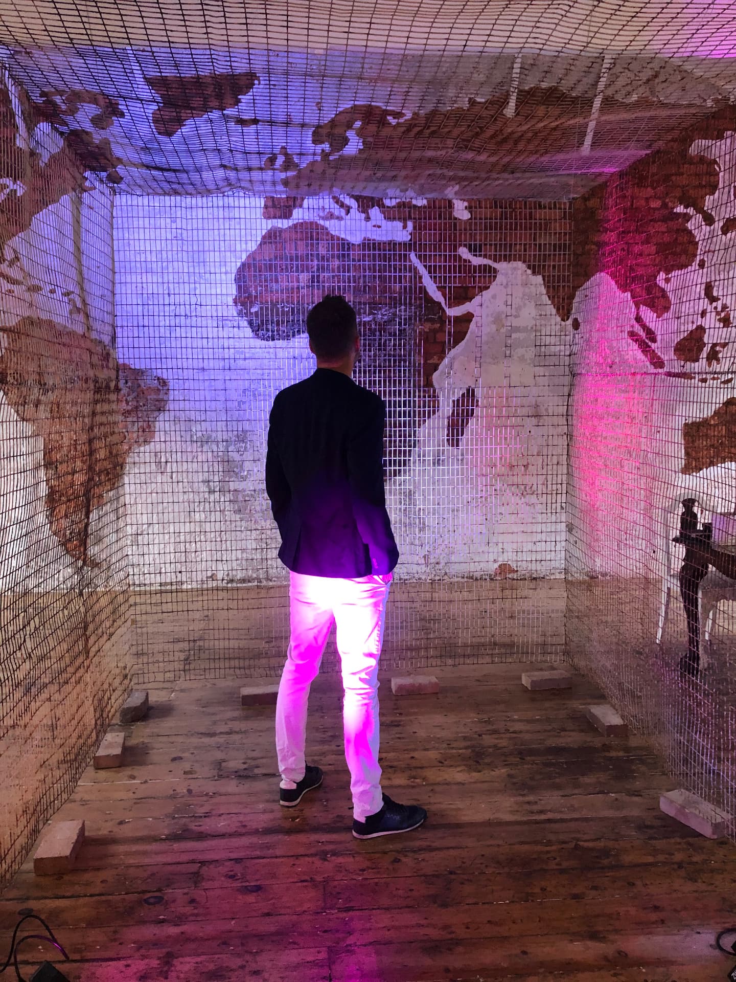 Standing before a world map, framed by borders — a reminder that knowledge should cross them